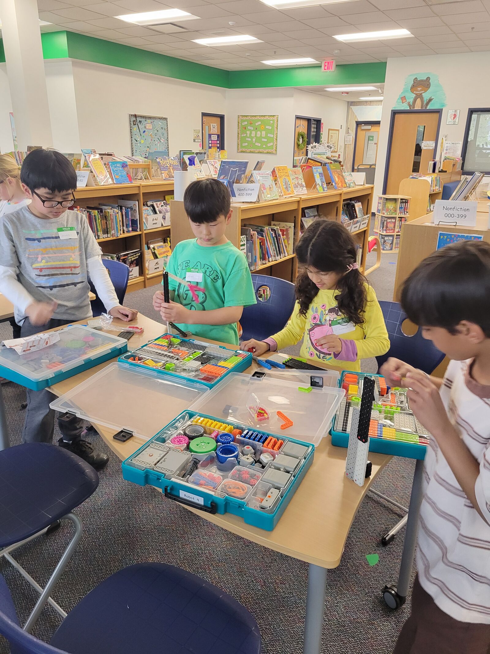 Students building with robotics kits at a school library table